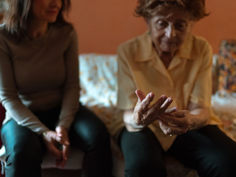 A caregiver and an older woman sitting close together on a couch